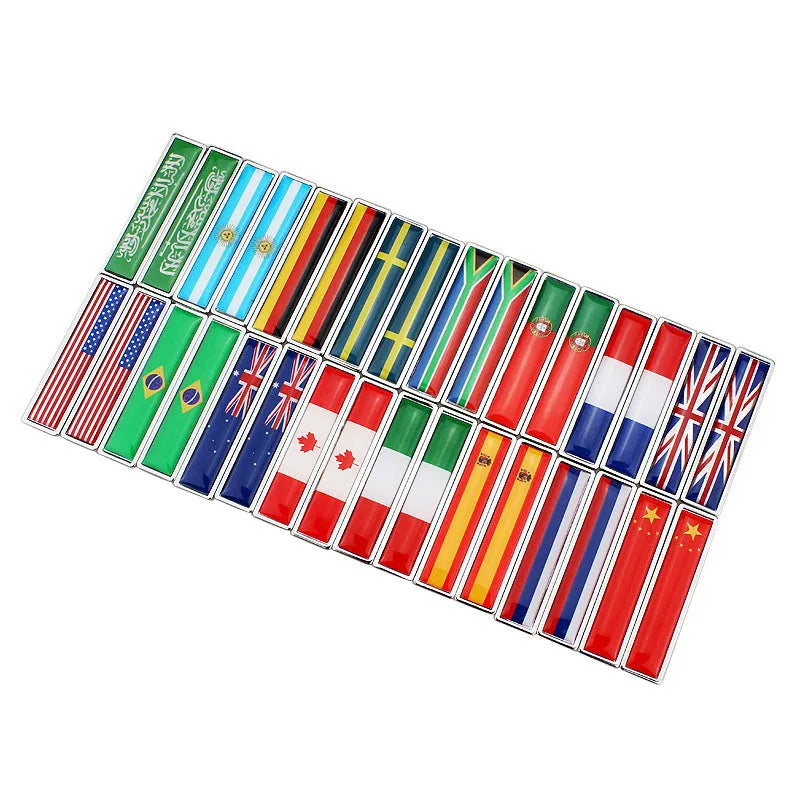 A pair of silver zinc alloy car badge labels with coloured national flag designs, shown at 58mm by 14mm scale.