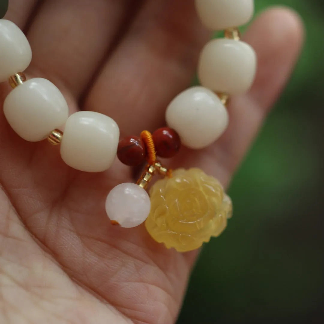 Close-up of a 10mm floral bracelet made from woven Bodhi root with gradient white jade and a natural beeswax lotus bead.