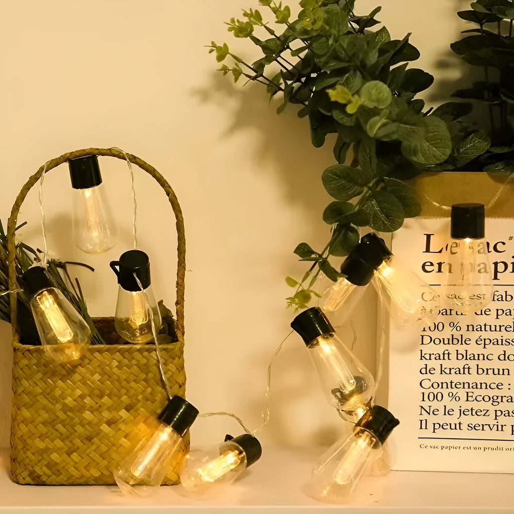 Outdoor retro string lights with glass infusion bottle bulbs hung along a black wire.
