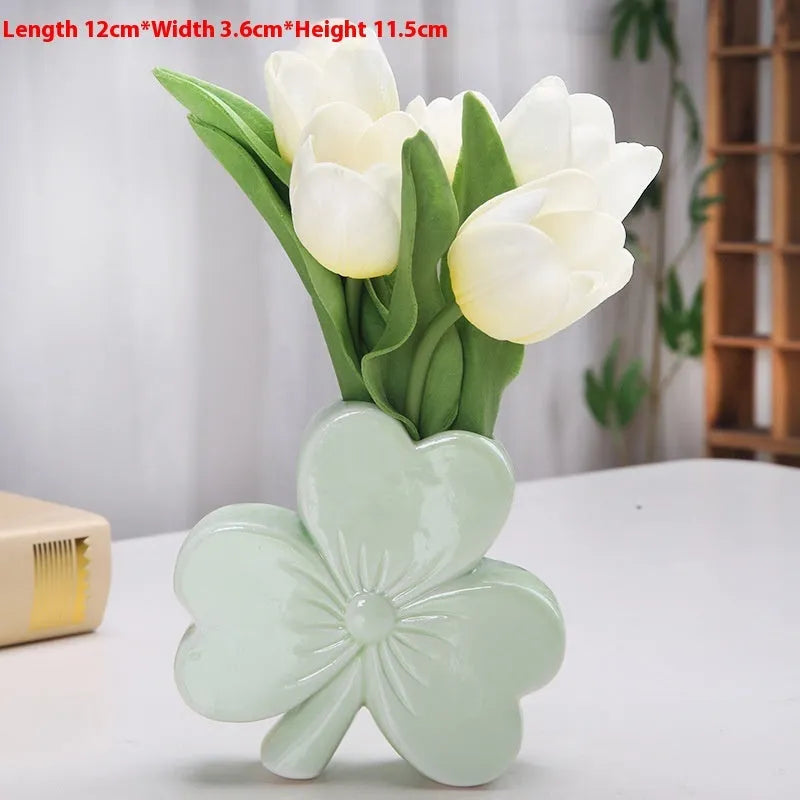 White porcelain clover-shaped ceramic vase in European style, on a desktop.