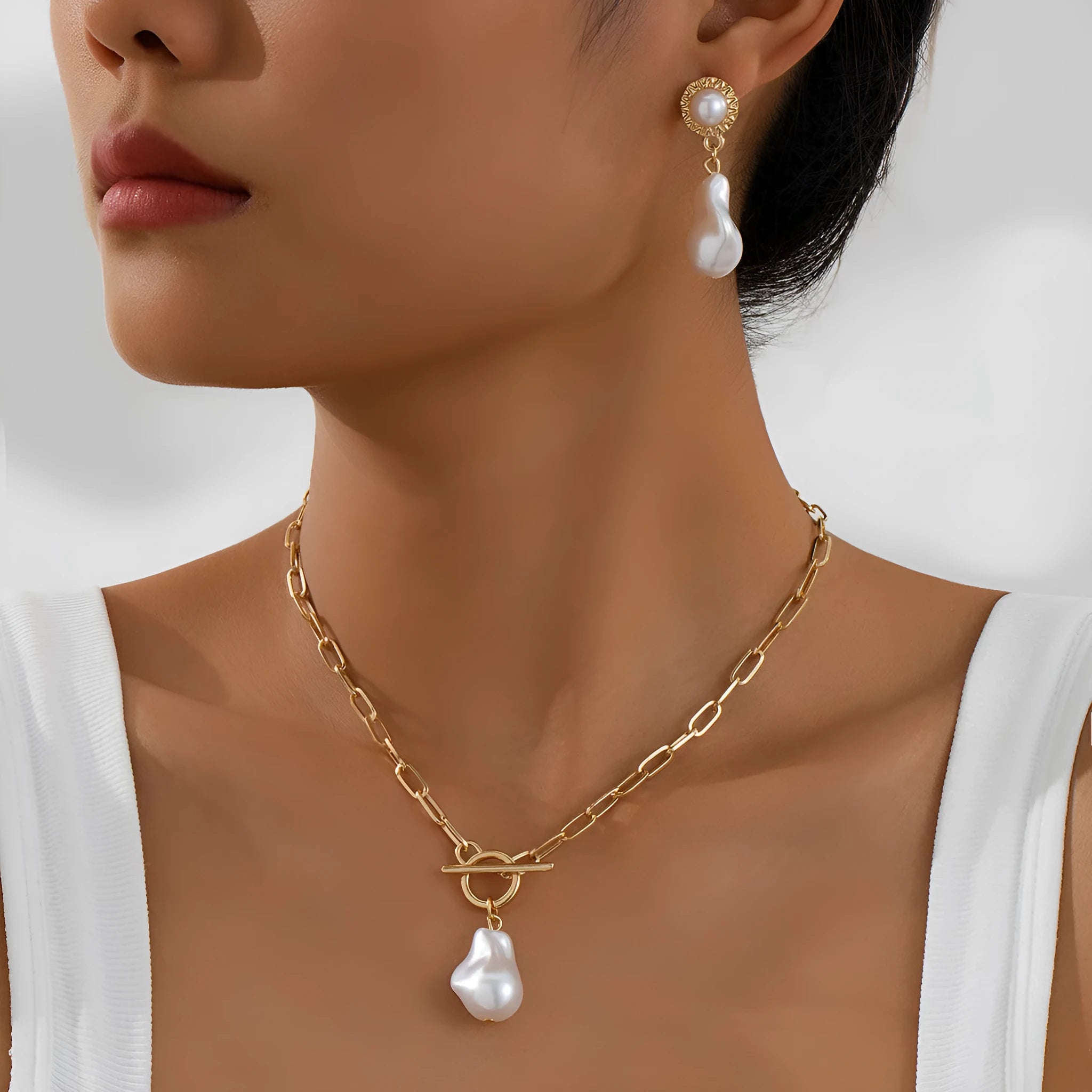 Gold-colour retro baroque pearl pendant necklace and matching ear studs set on a flat surface.
