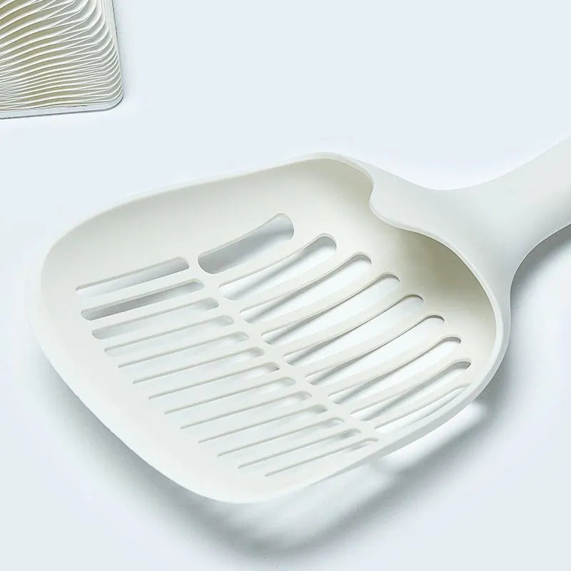 White plastic cat litter scoop with an integrated storage base on a flat surface.