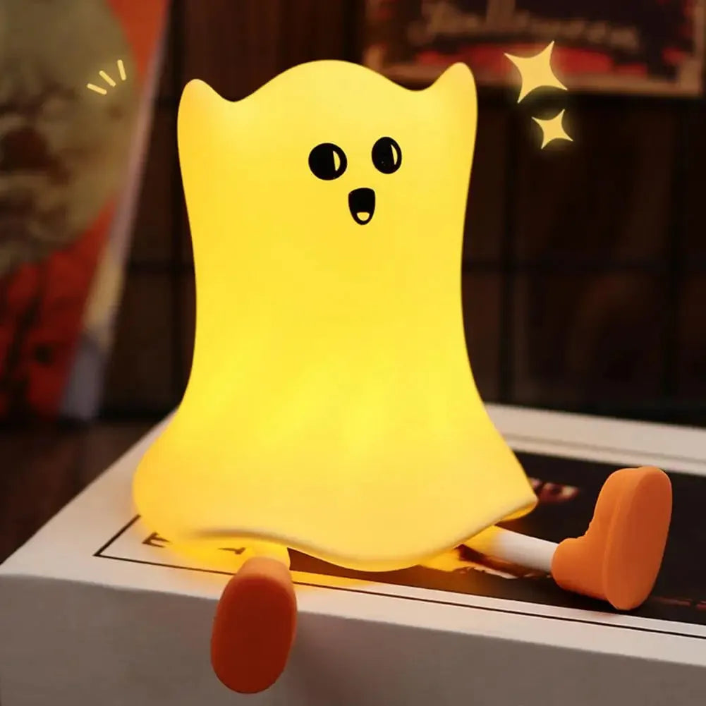 Cartoon ghost-shaped silicone bedside lamp with touch control, soft yellow glow on a bedside table