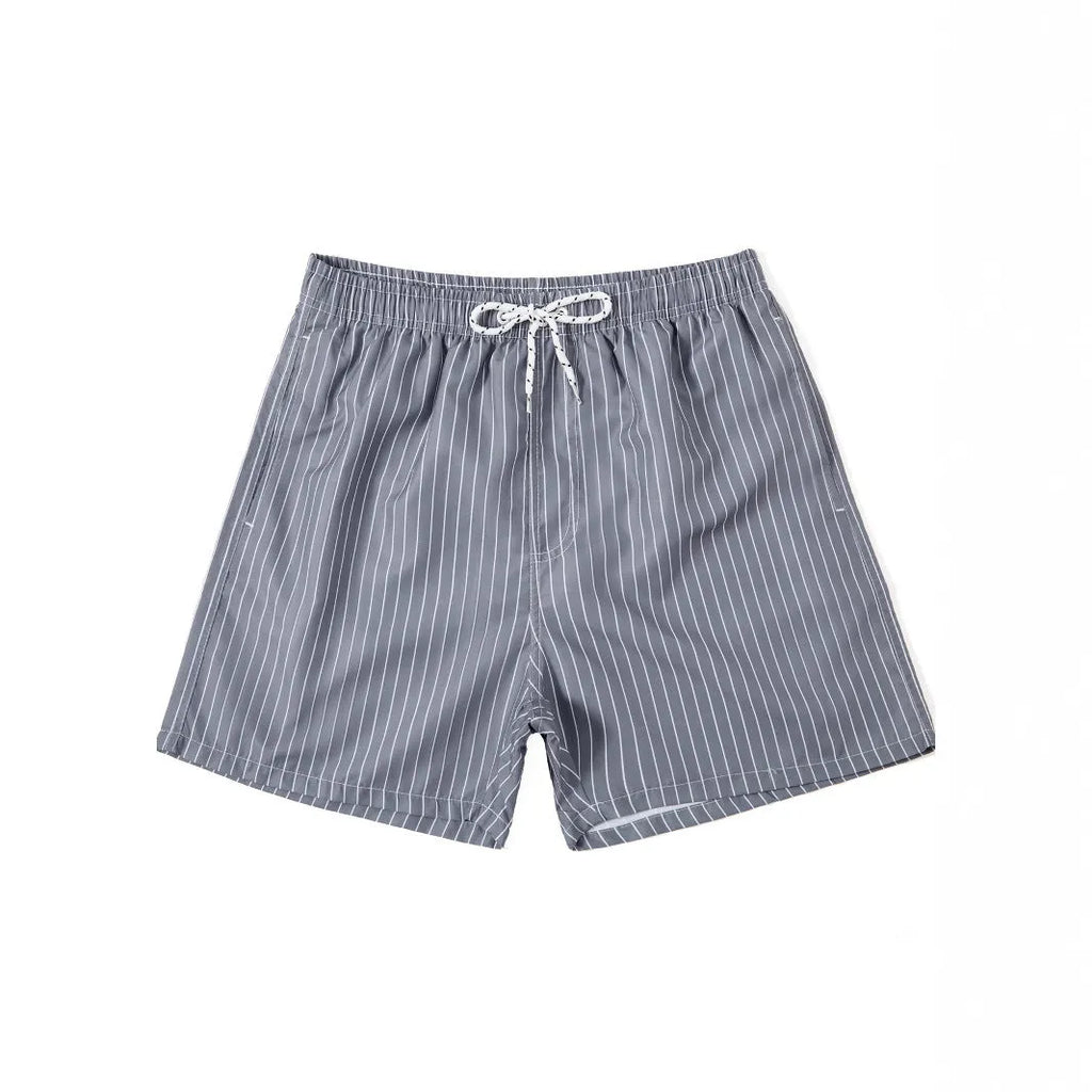 Men's striped polyester shorts in light blue, shown on a beach.
