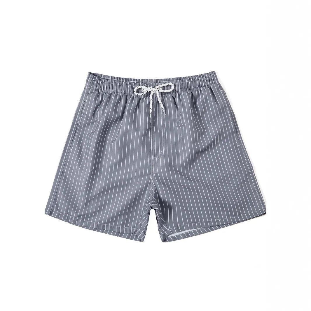 Men's striped polyester shorts in light blue, shown on a beach.