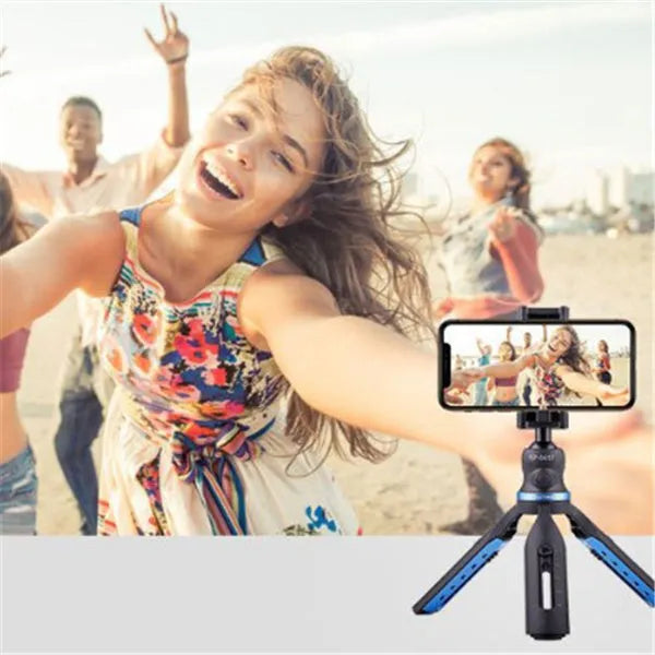 Black desktop tripod holding an iPhone, made from aluminium alloy and plastic, on a wooden table.