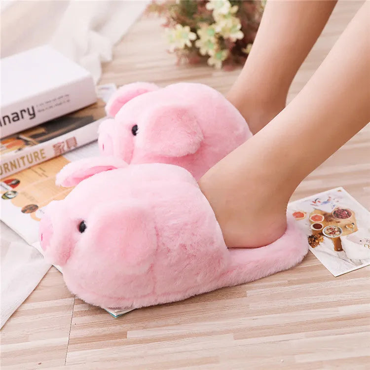 Pink pig-shaped plush floor slippers with soft filling on a plain background.