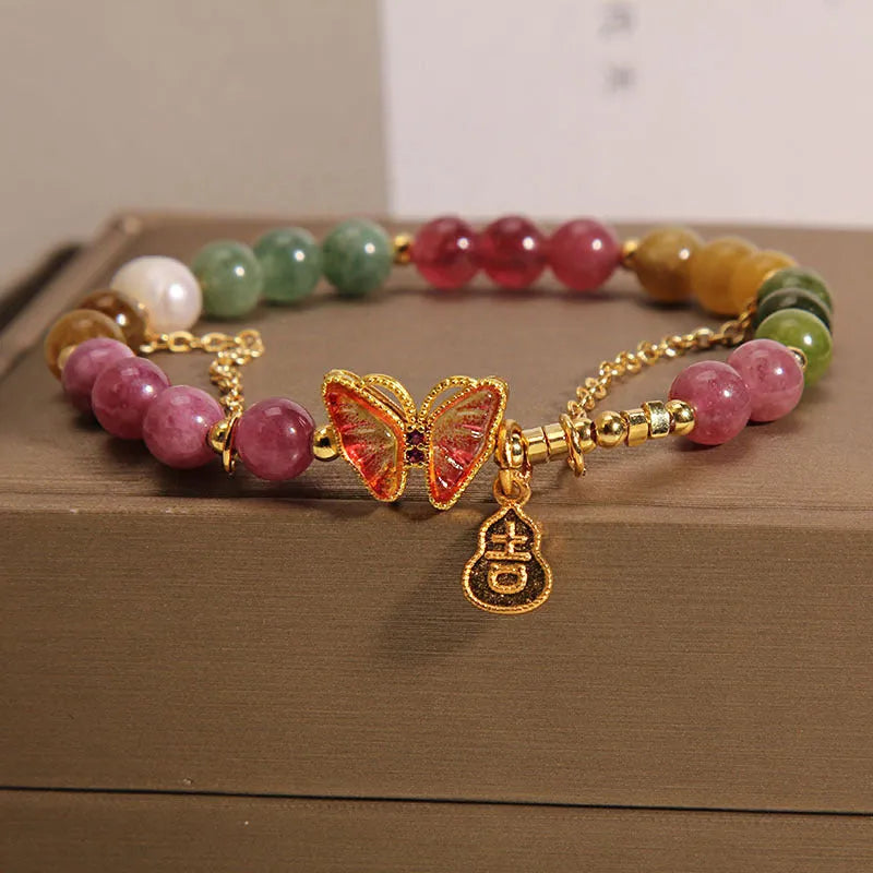 Close-up of a women's agate bracelet with a green tourmaline butterfly-shaped gourd charm on a white background.