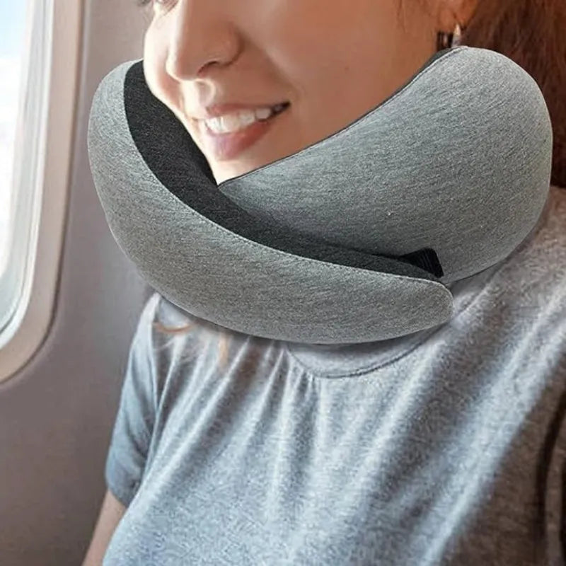 U-shaped navy blue memory foam travel neck pillow rolled up next to a mobile phone showing compact size