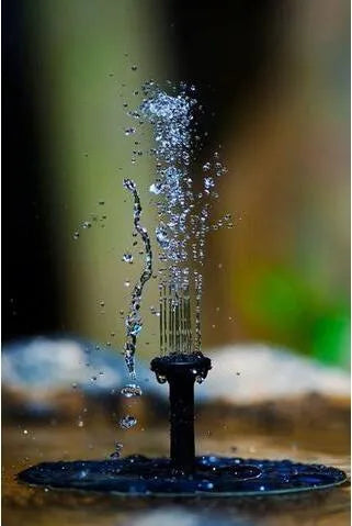 Black solar-powered water fountain pump with four spray nozzles, placed in a birdbath.