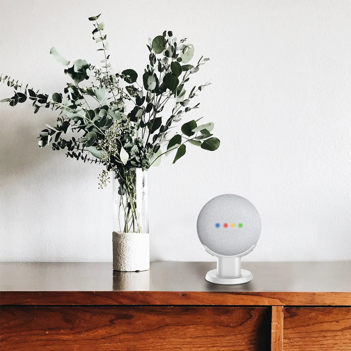 Black PlusAcc plastic stand holding a Google Home Mini speaker on a table.