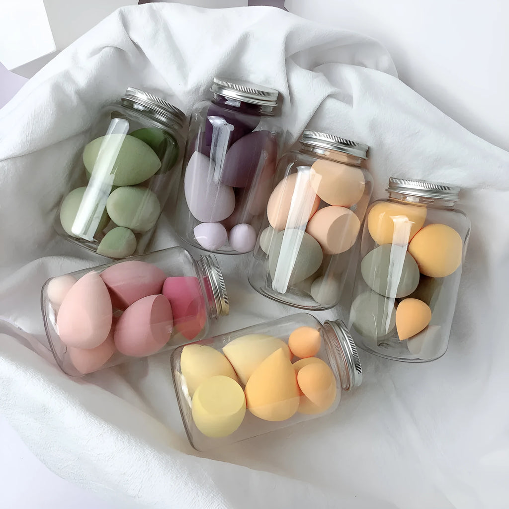 Set of 7 colourful makeup sponge eggs in a transparent jar against a white background
