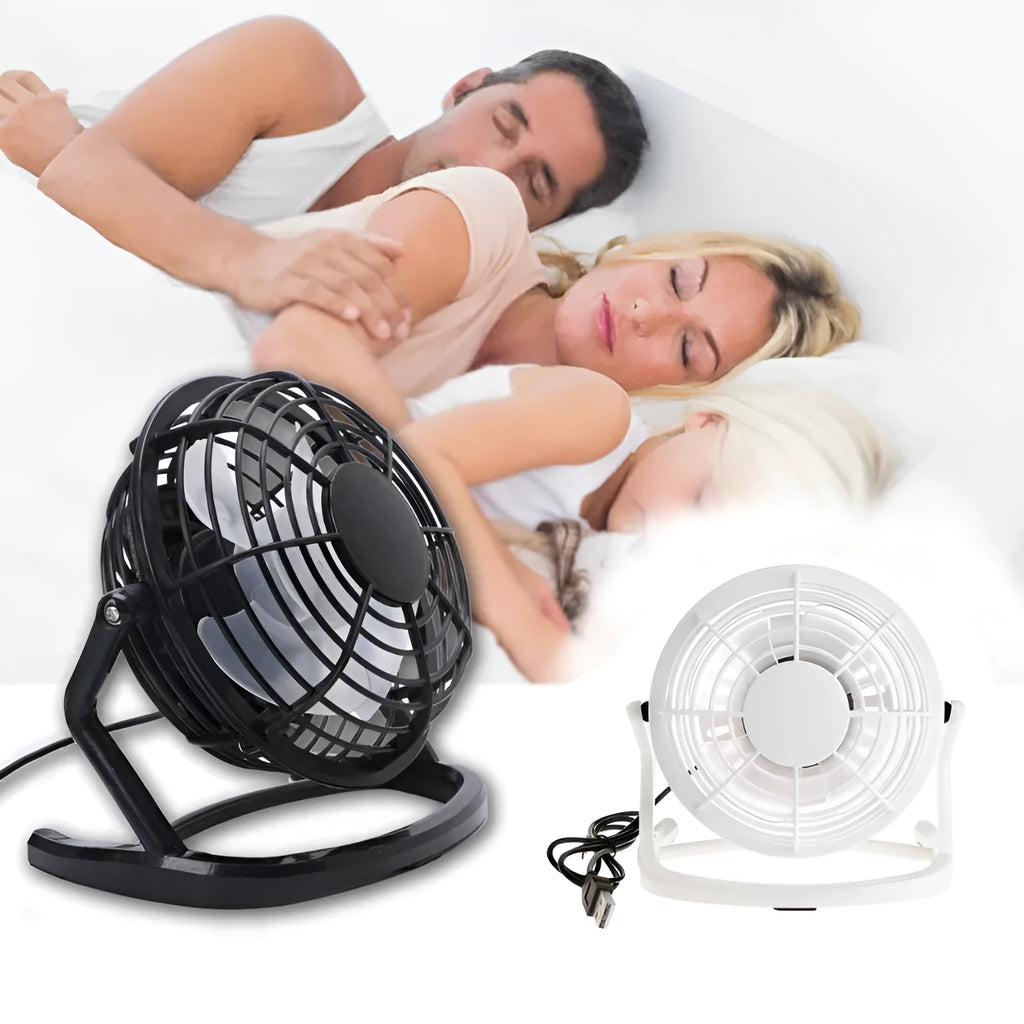 Mini black USB desk fan with adjustable tilt angle on a wooden desk next to a laptop.
