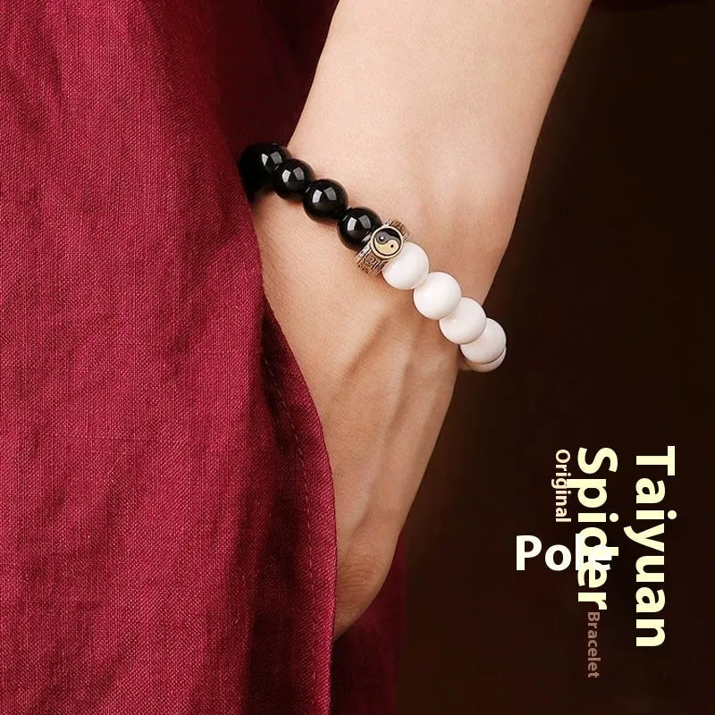 Black and white taiji bracelet with woven obsidian beads showing six word mantra and bagua symbol