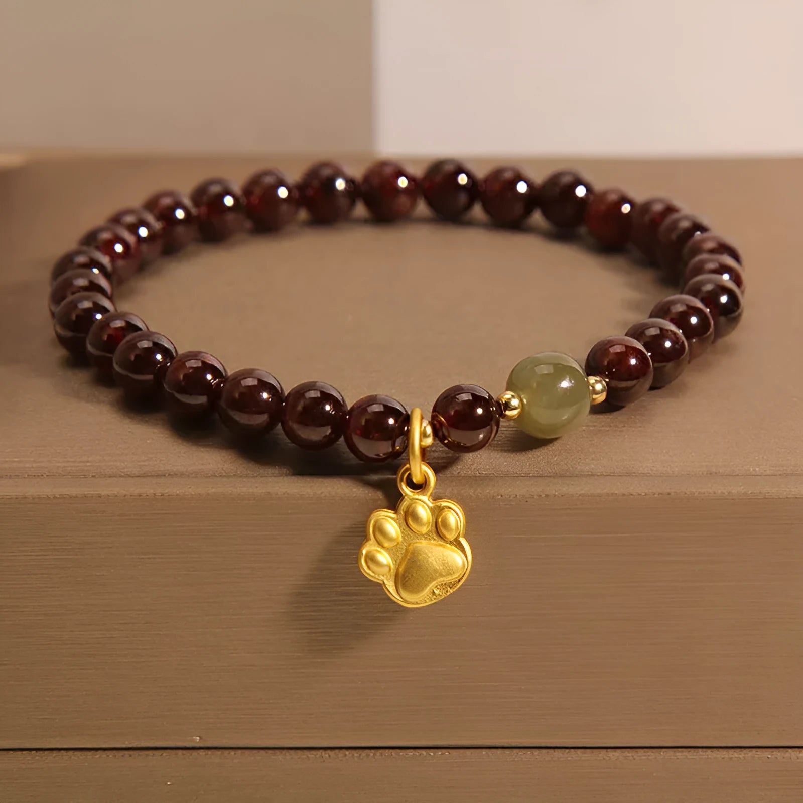 Women's original design Cat's Paw Garnet crystal bracelet on a plain background.