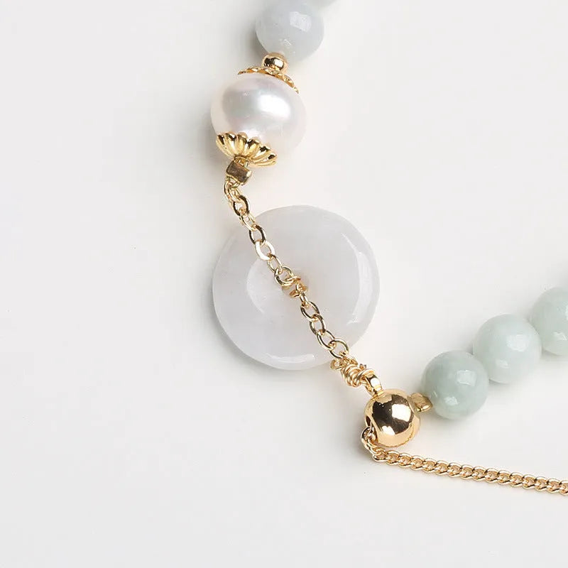 Natural jade bracelet with geometric shape, round pendant, and peace buckle closure on a wrist.