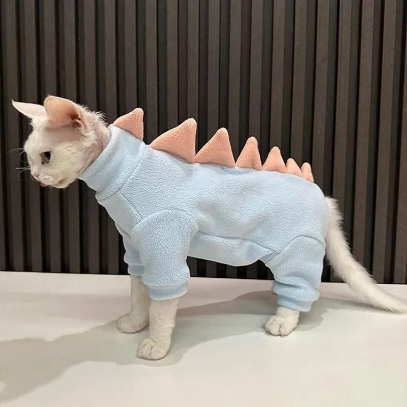 Sphynx cat wearing dinosaur costume with tail and back spikes, made from fleece material