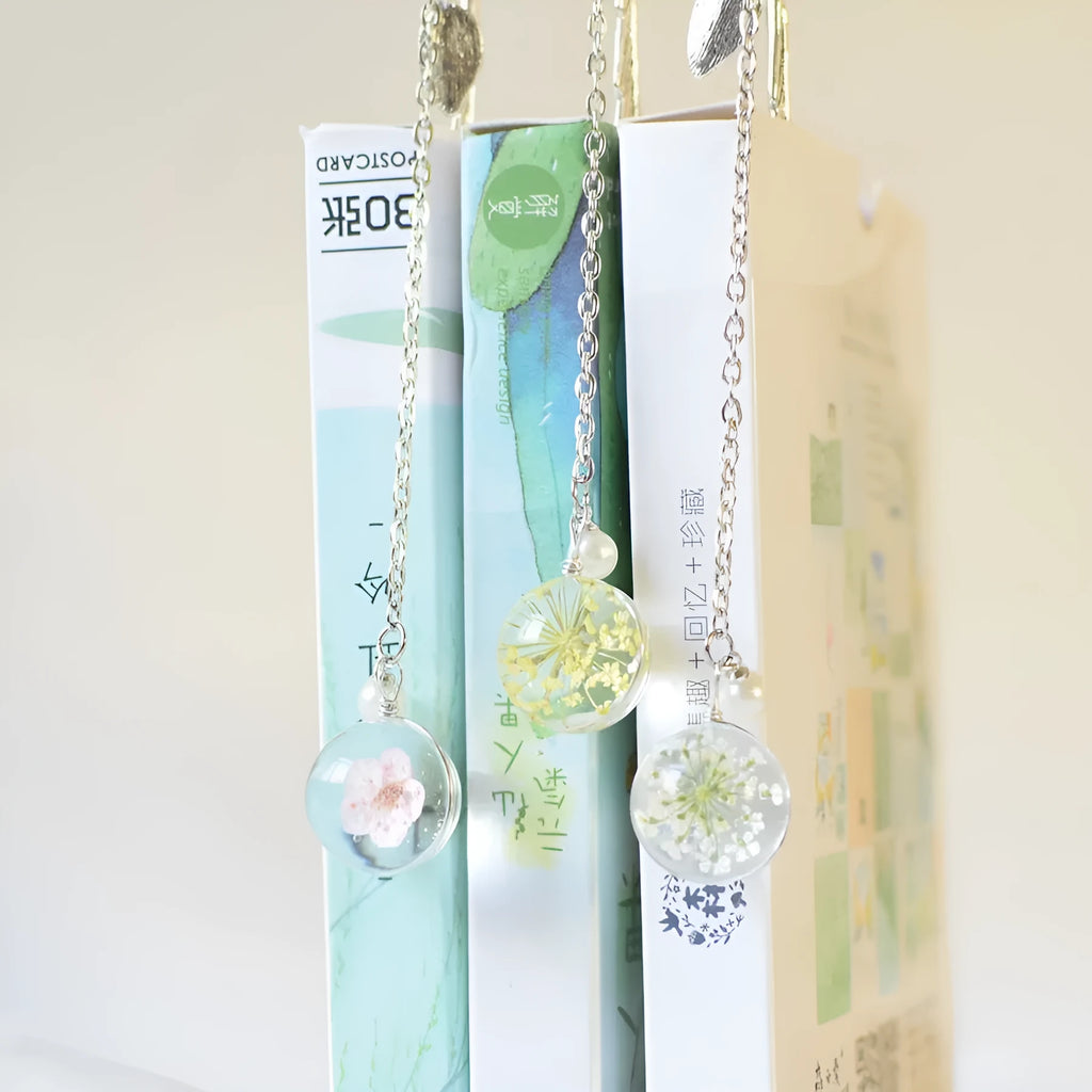 A close-up of a slim metal bookmark with a dried flower encased inside, showing its 12cm length.