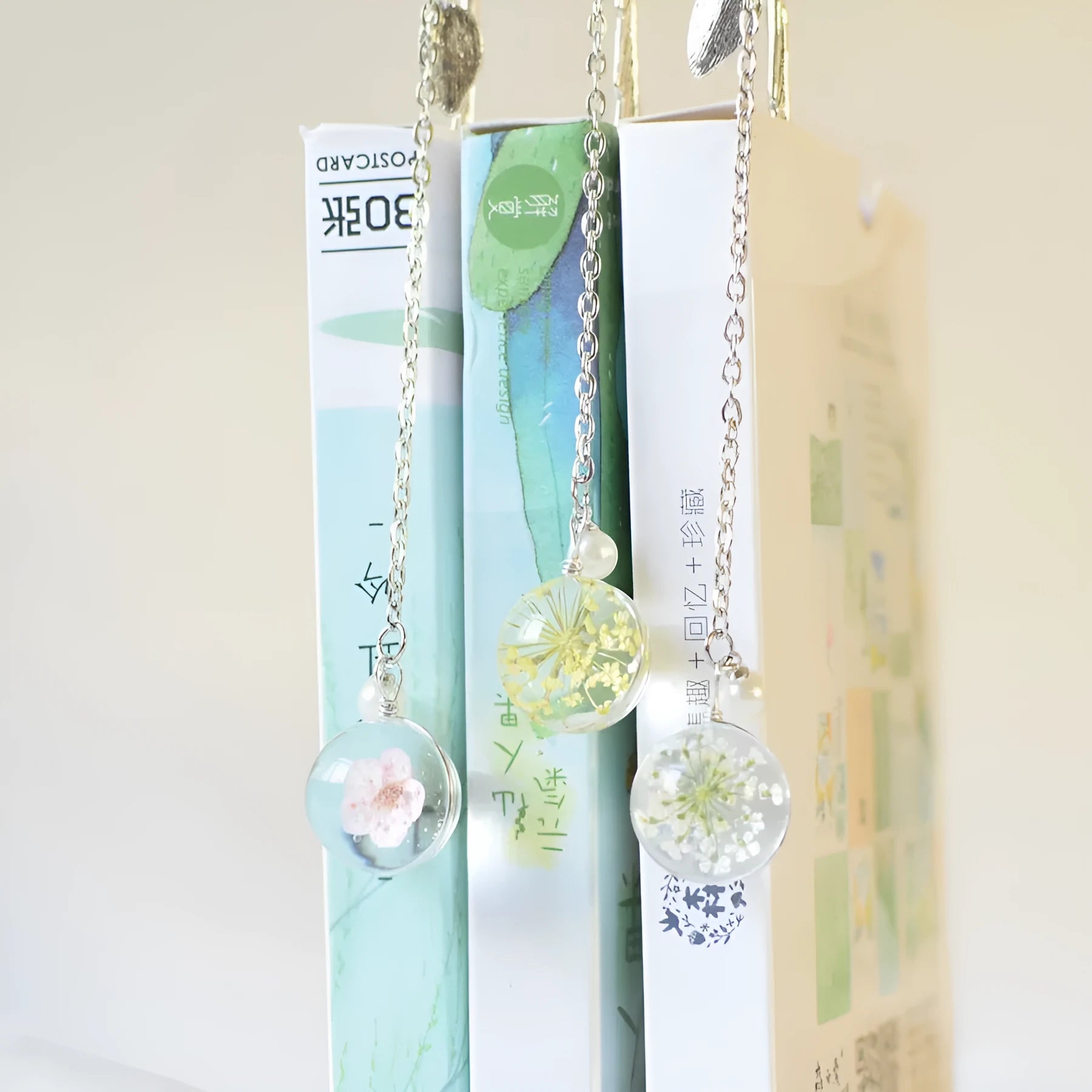 A close-up of a slim metal bookmark with a dried flower encased inside, showing its 12cm length.