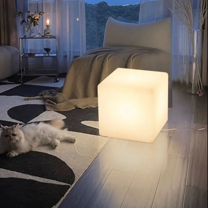A modern, square white LED cube light functioning as a waterproof outdoor stool.