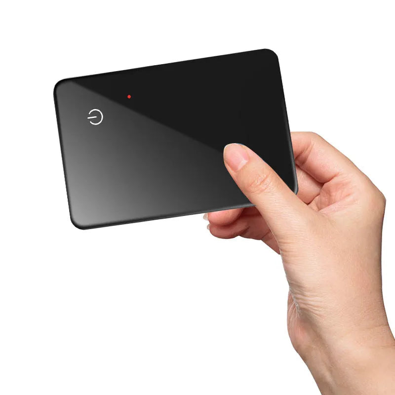 Black credit card-sized pet tracker with wireless charging and a hanging hole, shown next to a coin for scale.