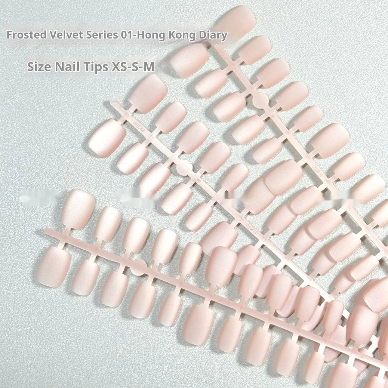 Set of frosted velvet Cat's Eye false nails in short ladder sizes XS, S, and M on a display stand.