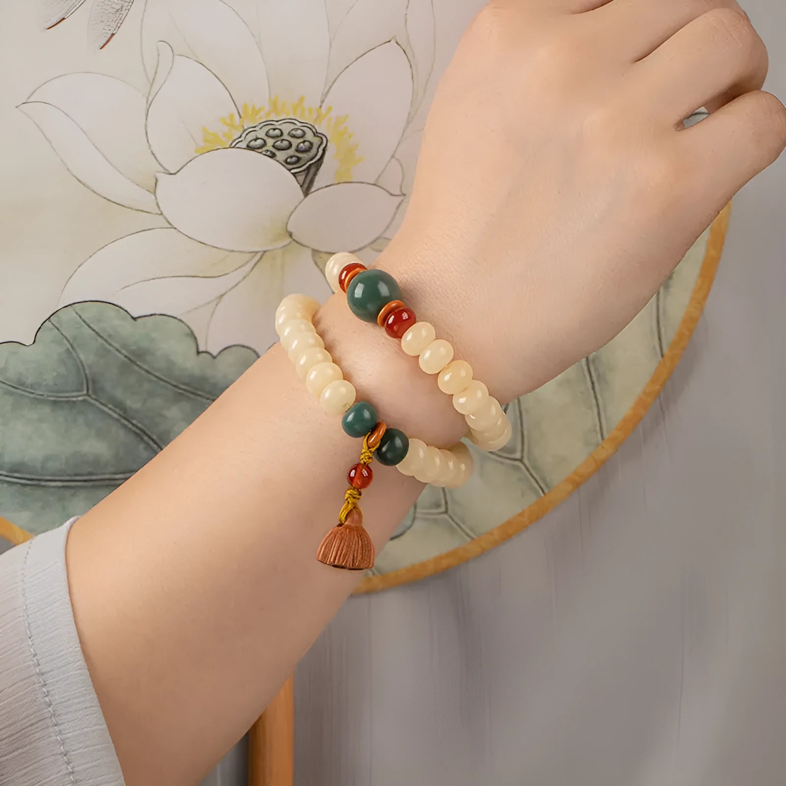 Cream topaz wooden bodhi root bracelet with flat round beads on a wrist.