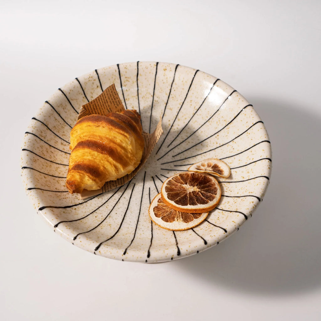Black and white striped retro style synthetic resin fruit plate on a wooden surface.