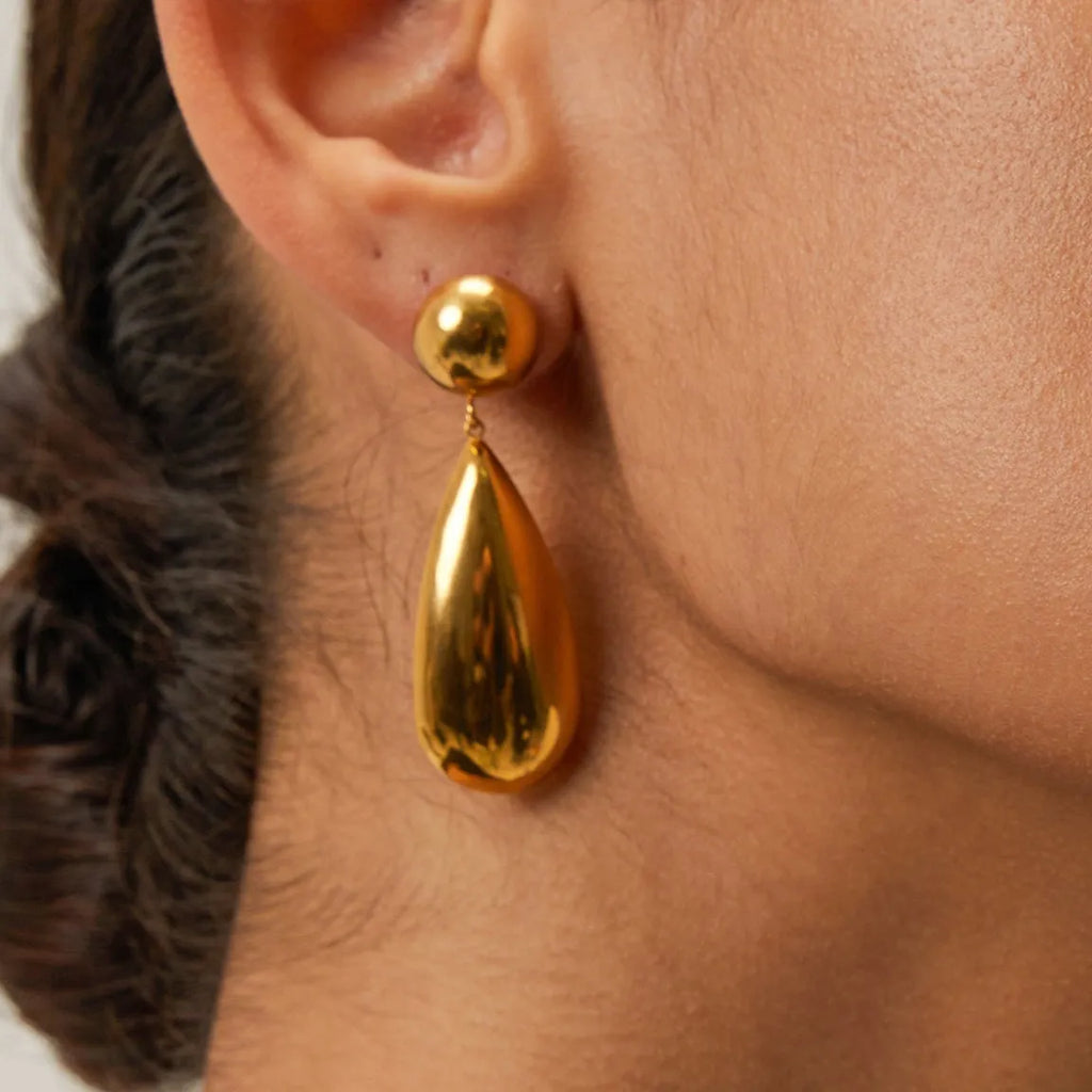 A pair of gold-coloured stainless steel earrings with a geometric water drop pendant design.