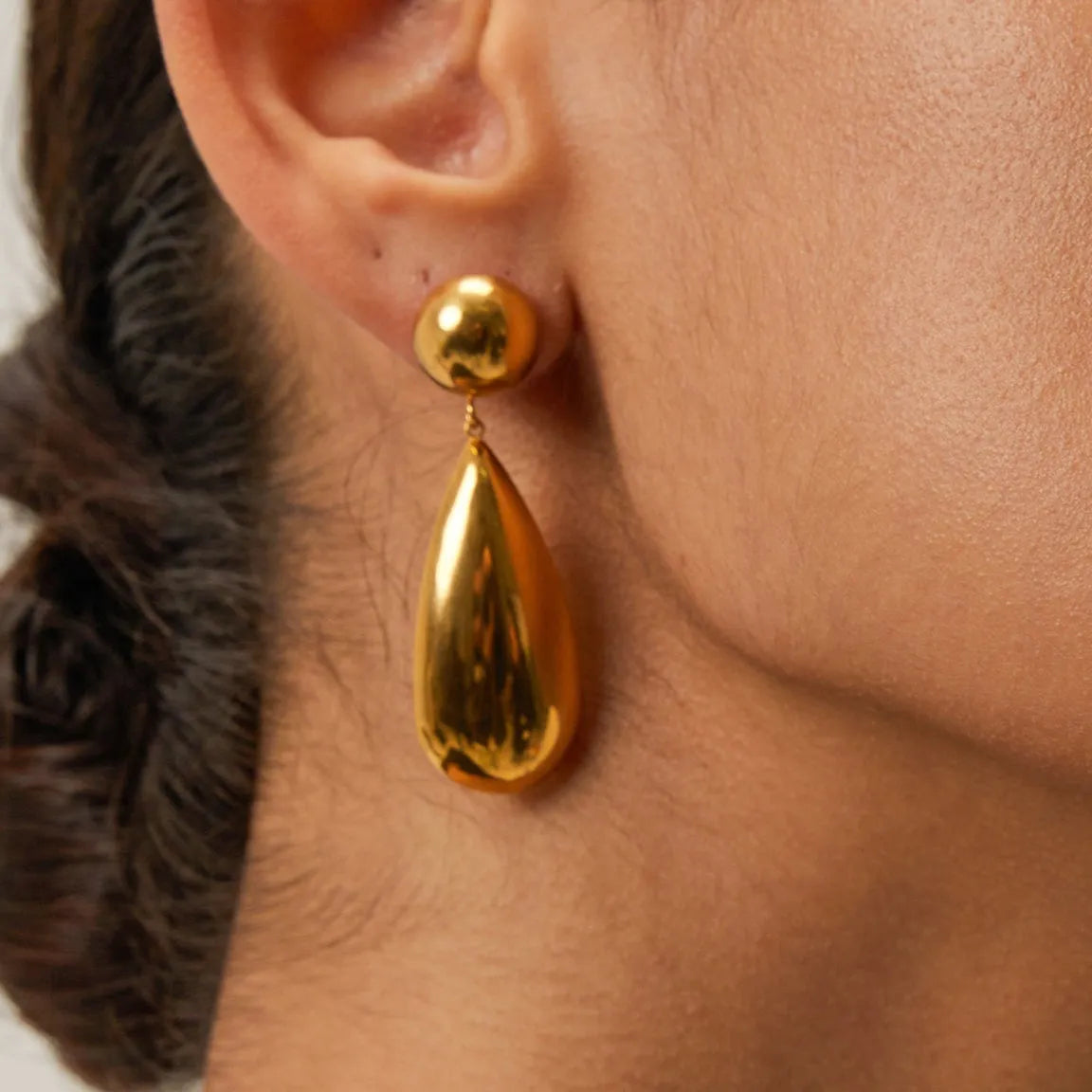 A pair of gold-coloured stainless steel earrings with a geometric water drop pendant design.