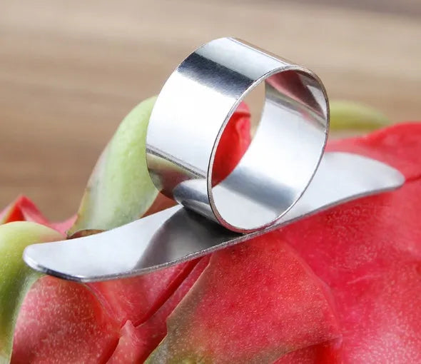Silver stainless steel fruit peeler ring for oranges, citrus, and pomegranates on a kitchen surface.