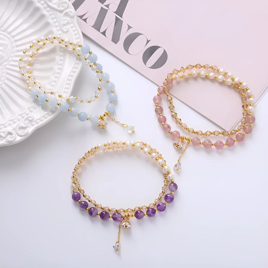 Close-up of a women's double ring bracelet with a freshwater pearl and amethyst crystal beads on a wrist.
