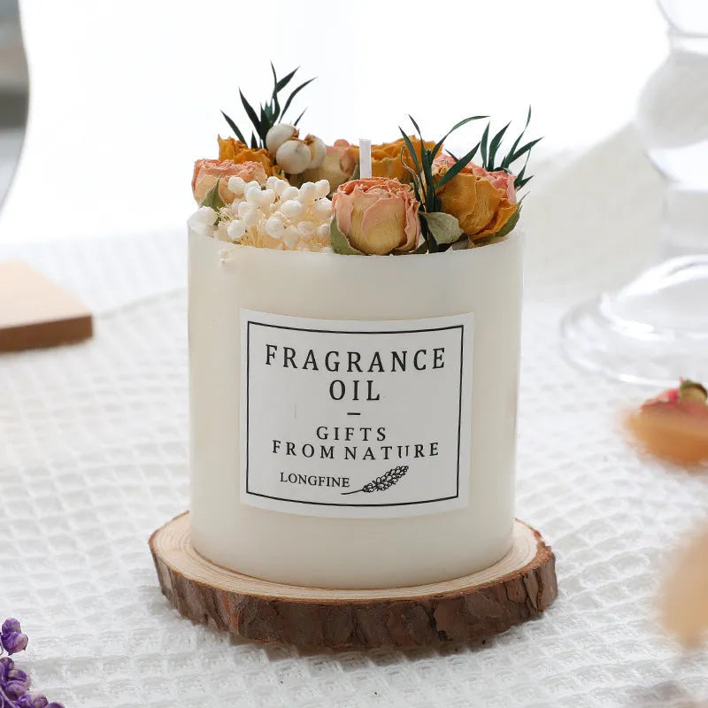 Decorative aromatherapy candle with dried flowers on surface, shown in gift box with chip base.