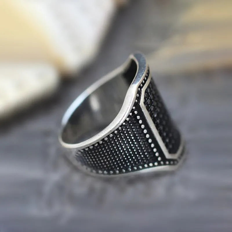 Black alloy ring with copper inlay and clear zircon stone accents on a hand.