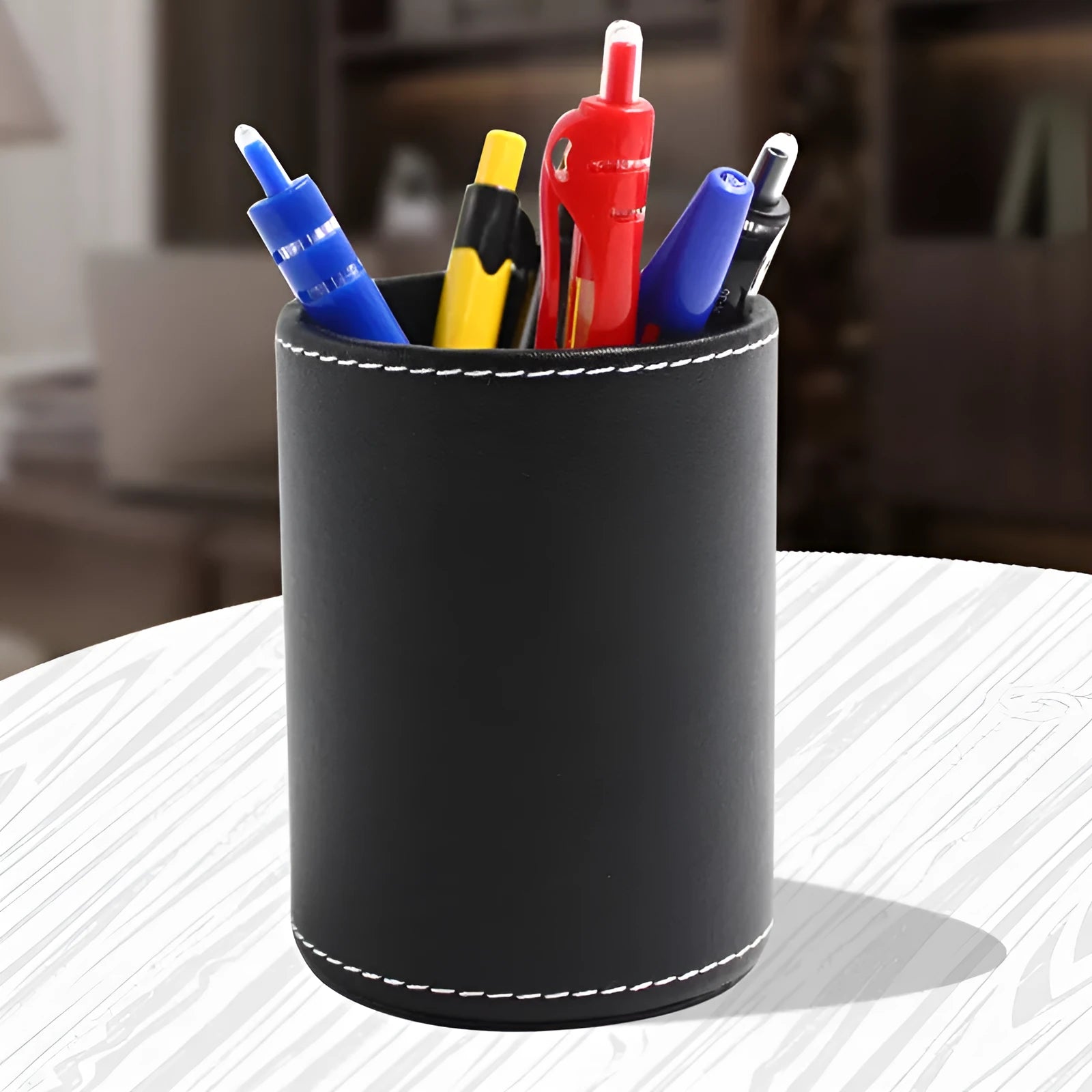 Small round black leather pen holder container showing cylindrical shape and compact dimensions