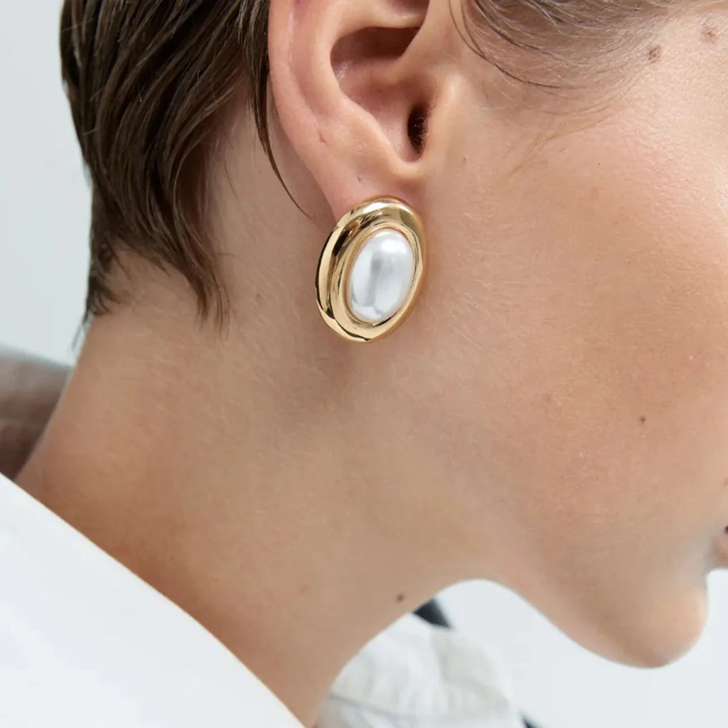 A pair of stainless steel vintage pearl stud earrings with a round pearl and electroplated finish.