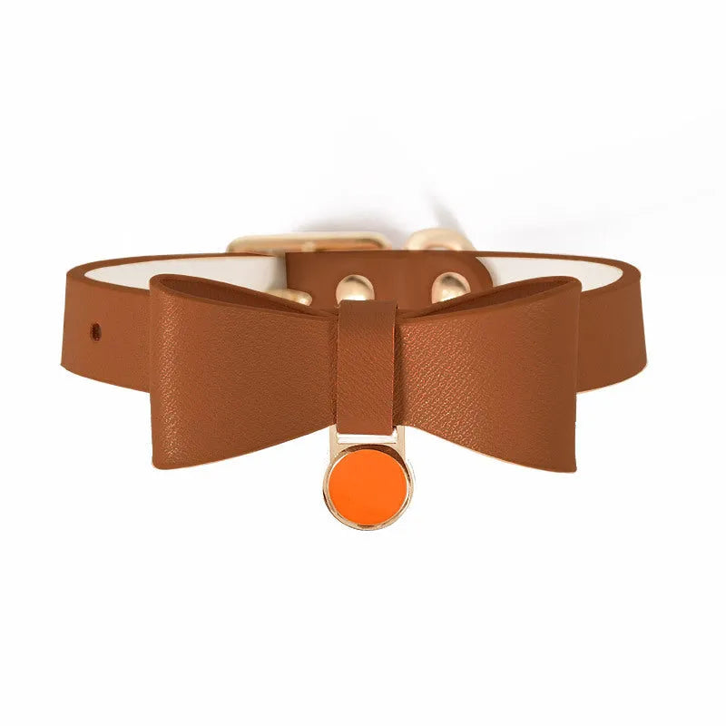 Brown leather cat collar with a metal bell on an adjustable strap.