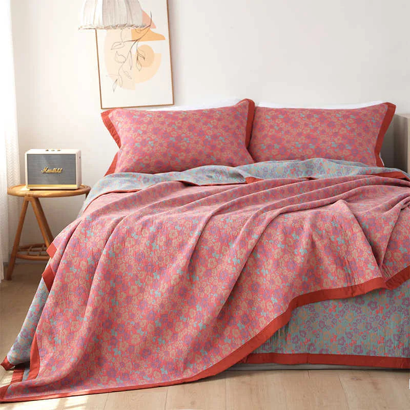 Cotton gauze bed blanket set with floral pattern and two matching pillowcases laid on a bed