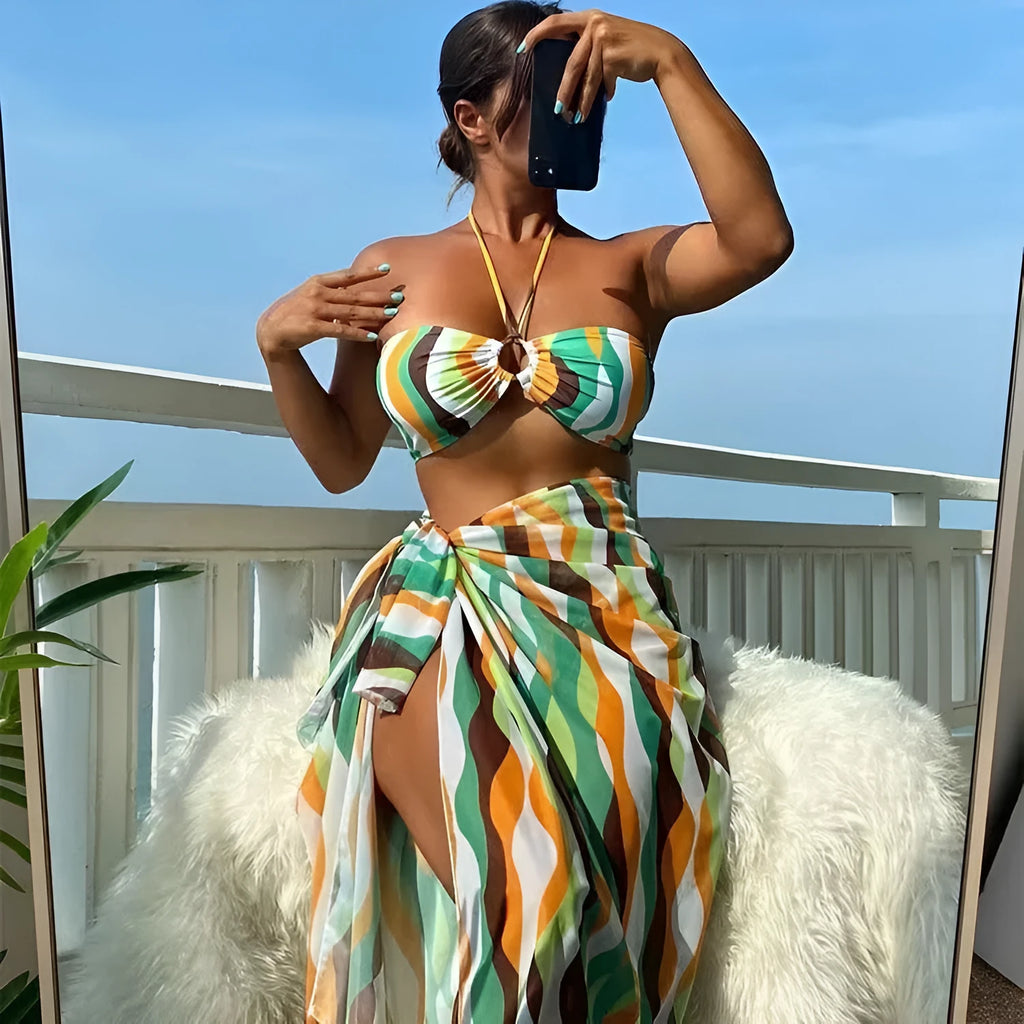 Women's yellow green printed three-piece bikini set with matching beach skirt laid flat.
