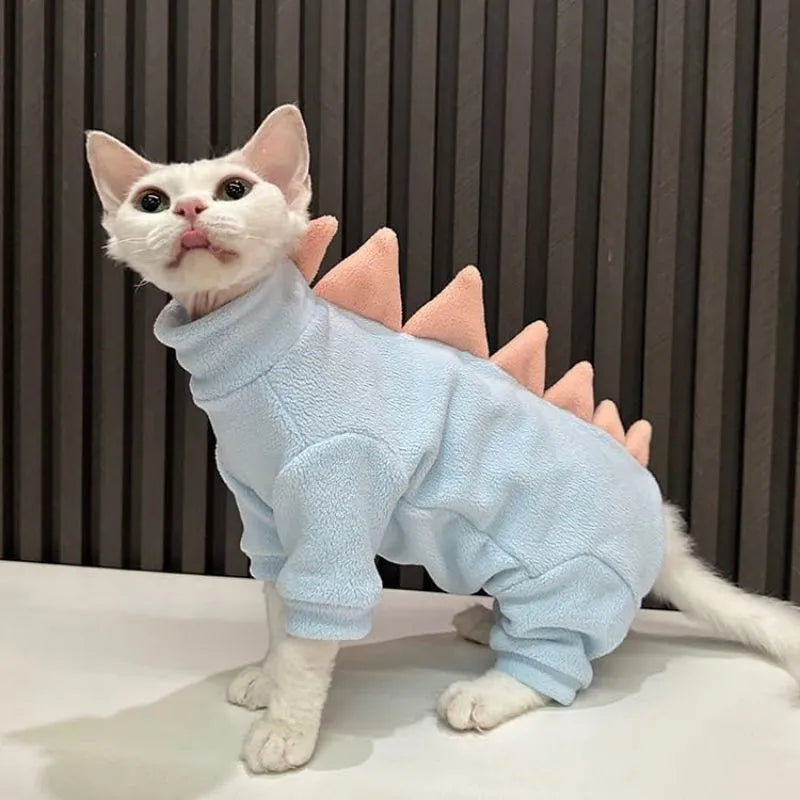 Sphynx cat wearing dinosaur costume with tail and back spikes, made from fleece material