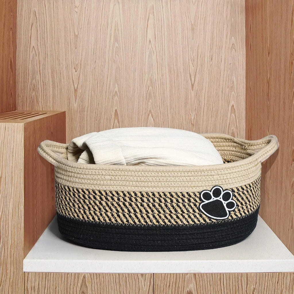 Handmade light beige cotton rope woven storage basket with handle on a wooden surface
