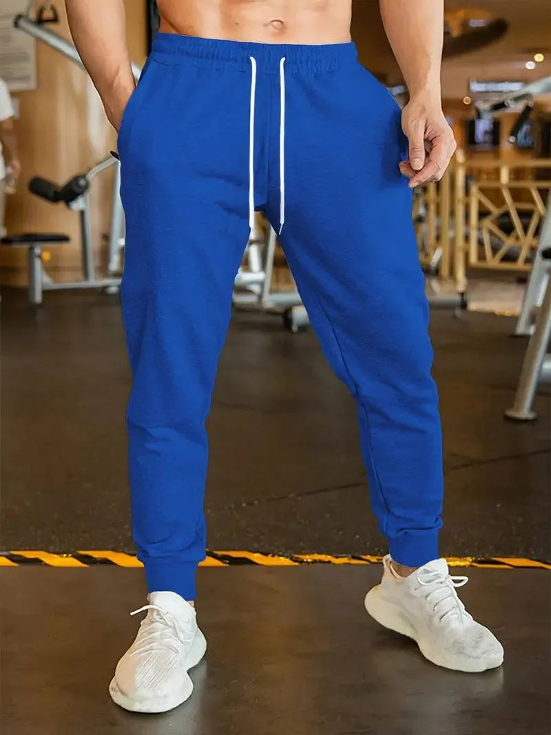 Man wearing grey loose-fit linen-style leisure trousers with an elastic drawstring waistband.