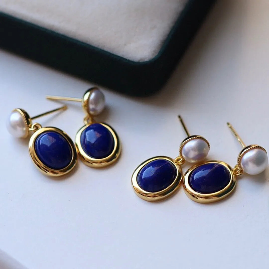 A pair of simple sterling silver stud earrings with a blue lapis lazuli pearl drop.