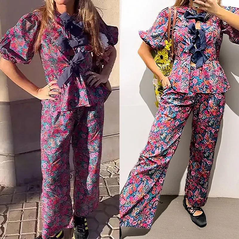 Women's floral print trouser suit set with tie-neck top and puffed sleeves.