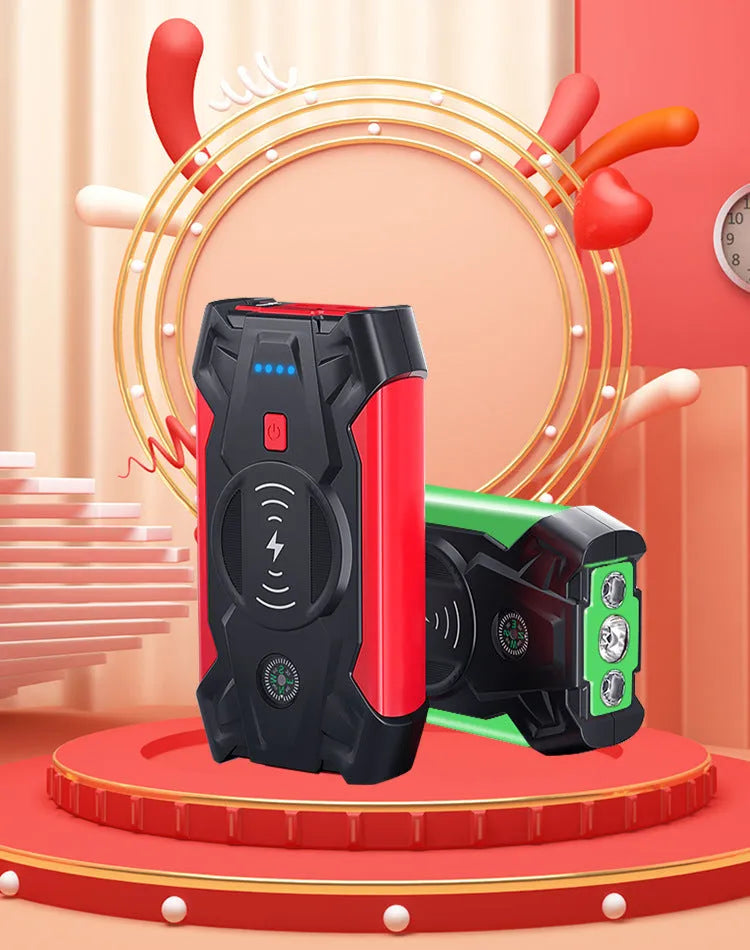 Red car emergency jump starter power pack with battery clamps and cables on a black storage box.