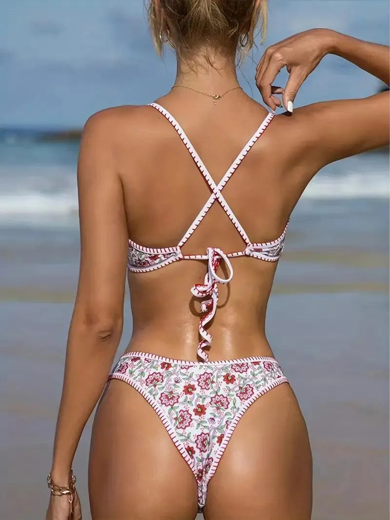 Women's one-piece swimsuit with V-neck embroidery and floral print on blue background.