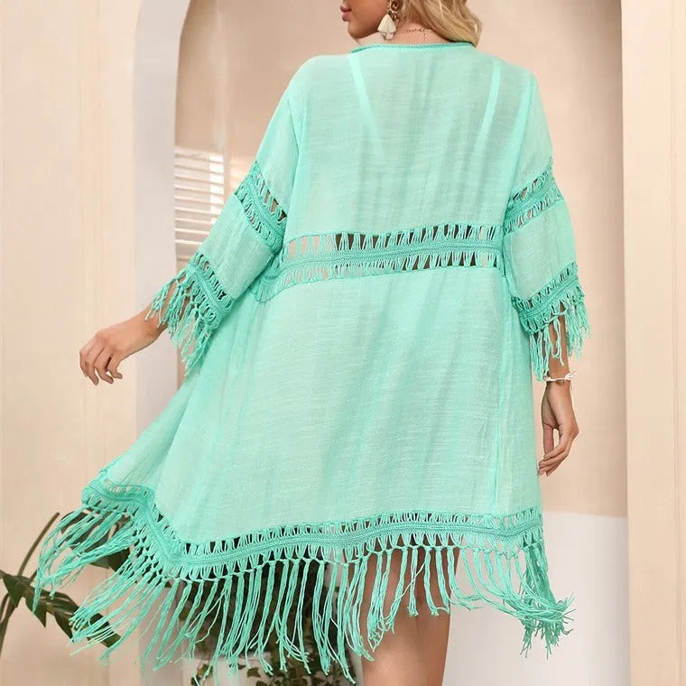 Women's yellow hand-crocheted beach cover-up cardigan with loose stitching and tassels on a hanger.