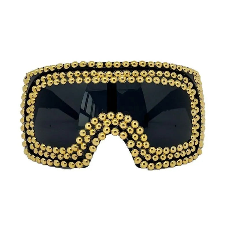 Men's square punk sunglasses with large rim and silver rivets on a dark background.