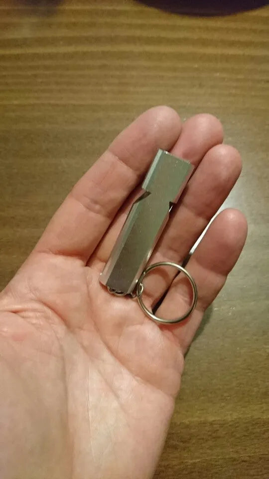 Silver or gold coloured aluminium alloy double hole outdoor survival whistle.