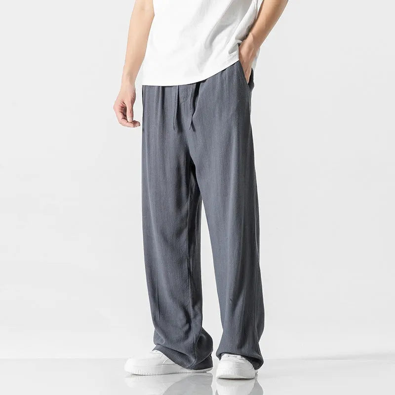 Man wearing beige cropped straight-leg linen trousers with a drawstring waist.